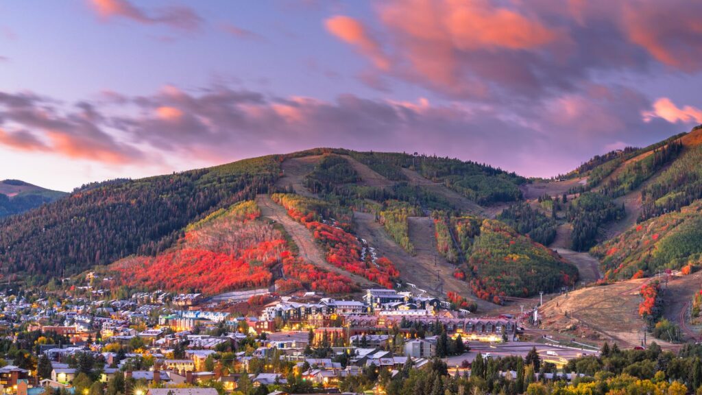 A mountain town in Summit County at dusk, with ski runs on the hillside above it