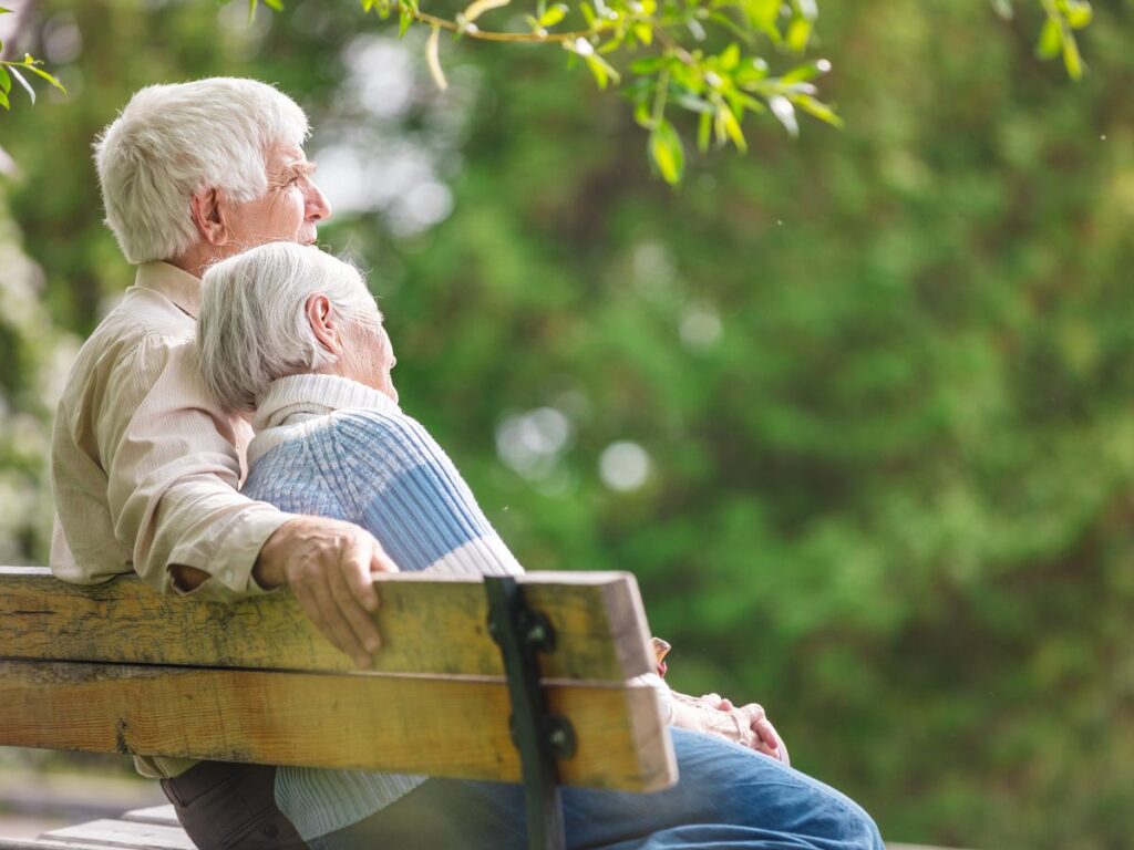 An older couple sitting together on a bench outdoors